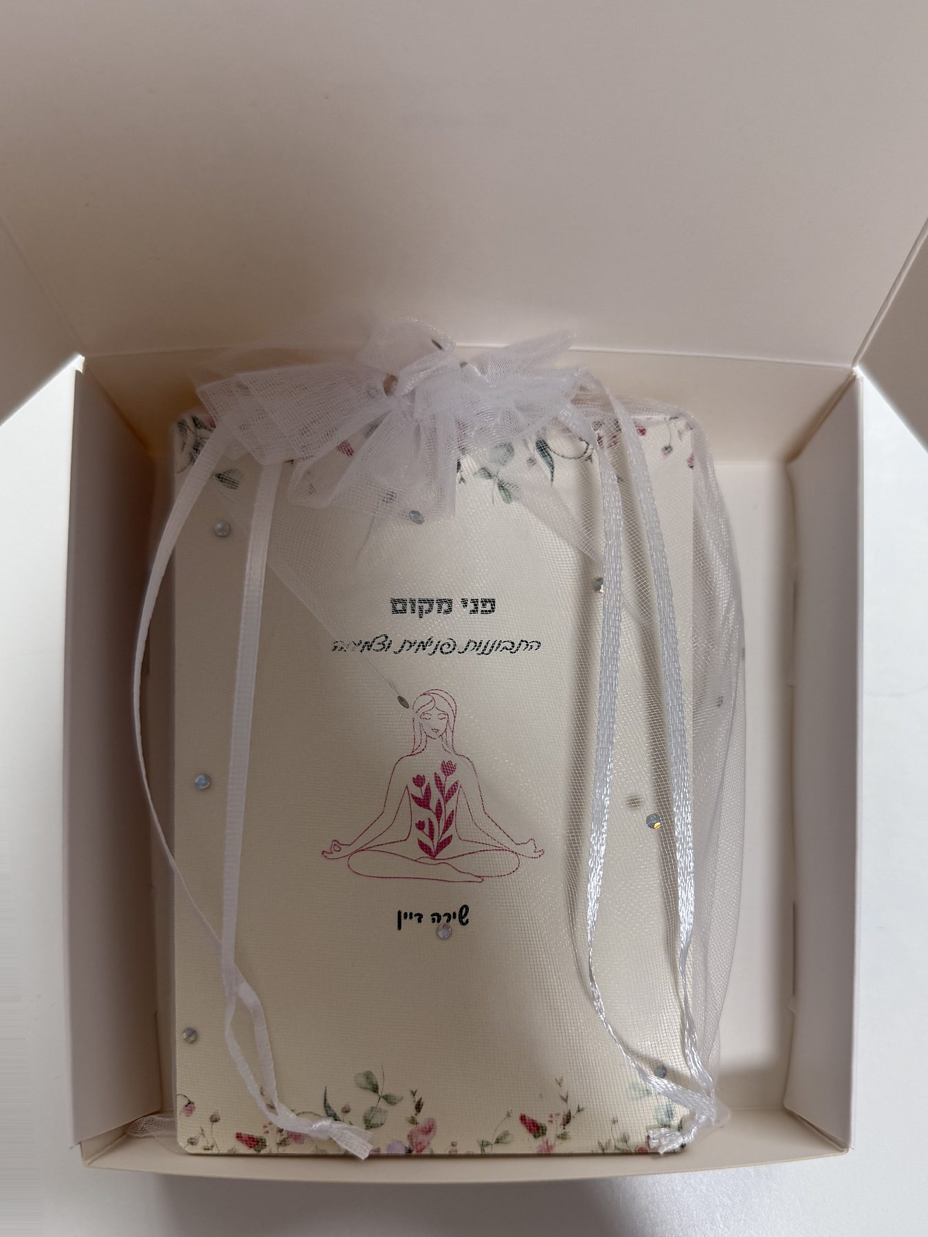 קופסת פני מקום פתוחה, ובתוכה ערכת הקלפים עטופה בשקית אורגנזה פרחונית וסרט טול לבן