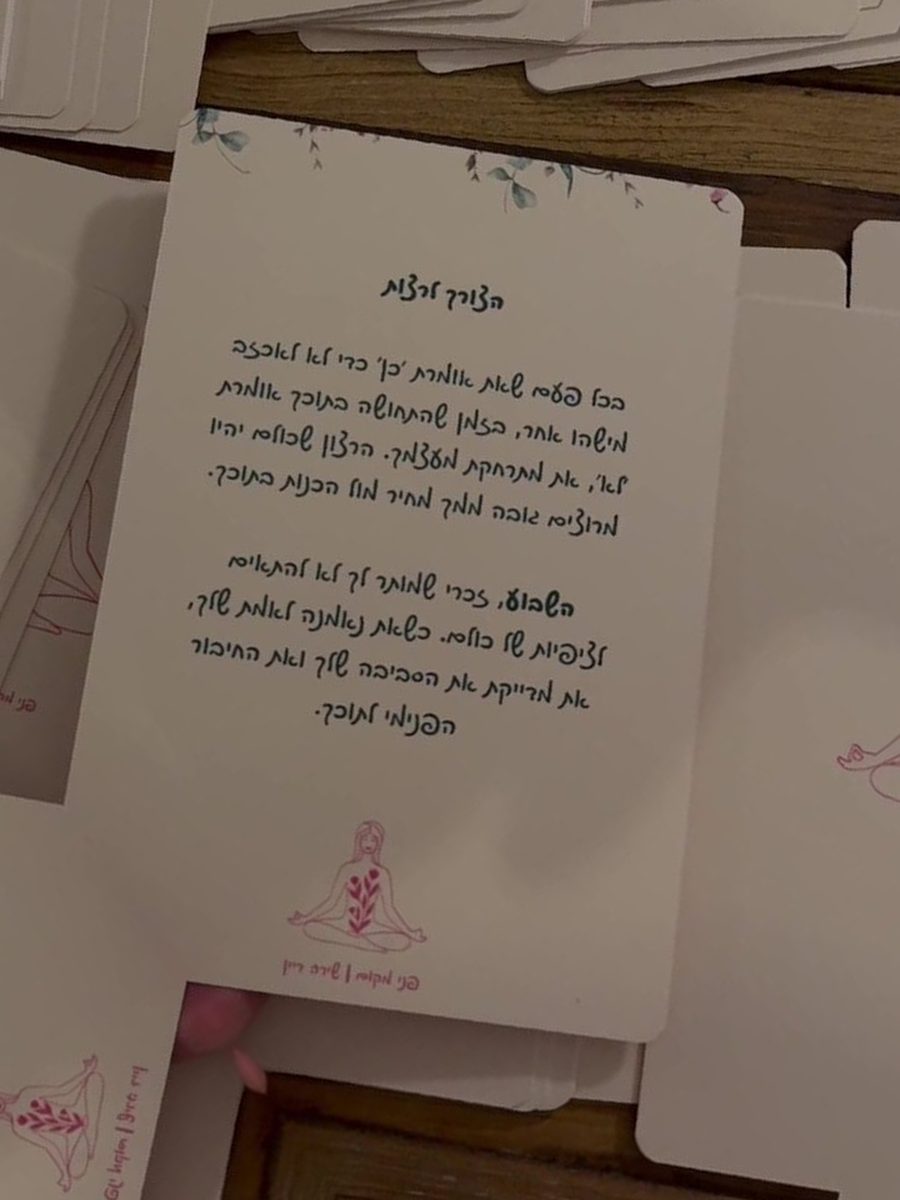 הקלפים פרוסים על שולחן עץ, קלף אחד הפוך וטקסט ההתבוננות שלו גלוי